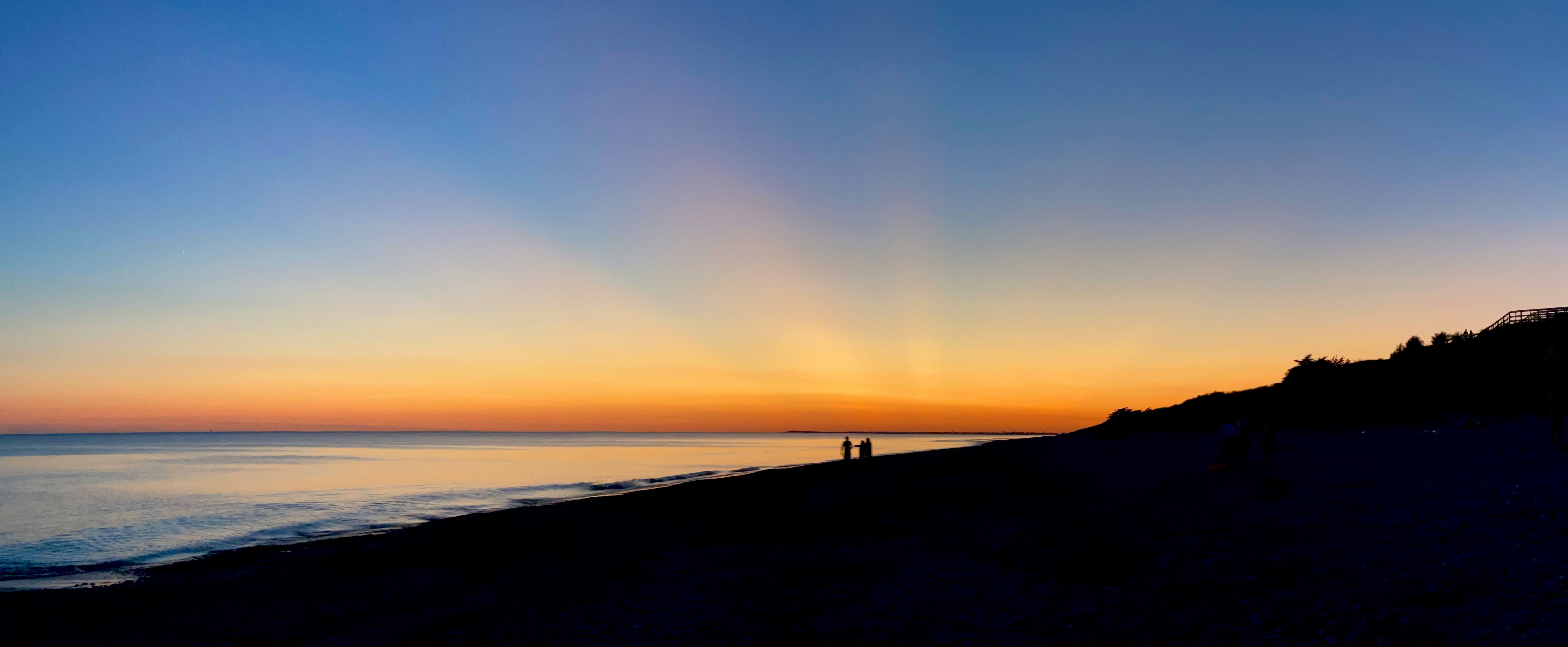 silhouette of person standing on seashore during sunset